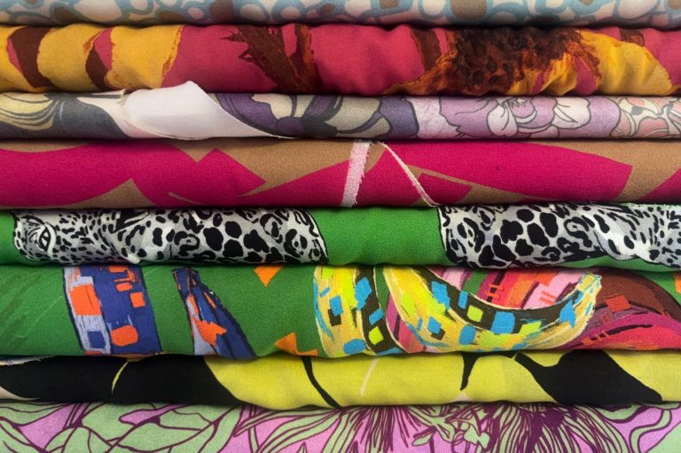 Bunte Stoffe in verschiedenen Mustern und Texturen übereinander gestapelt.