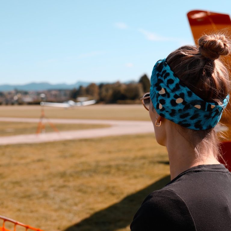 Frau mit einem blauen Kopfband schaut auf ein Flugfeld mit Flugzeugen im Hintergrund.